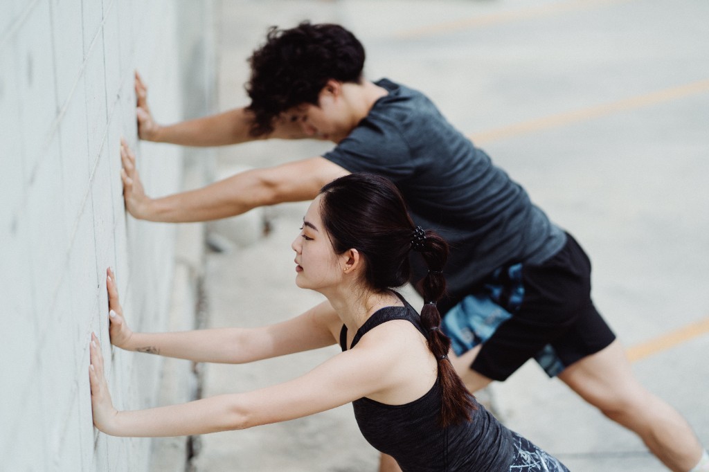 Woman performing a calf stretch against a wall — resistance training creates mechanical tension when muscle fibers produce force against a load
