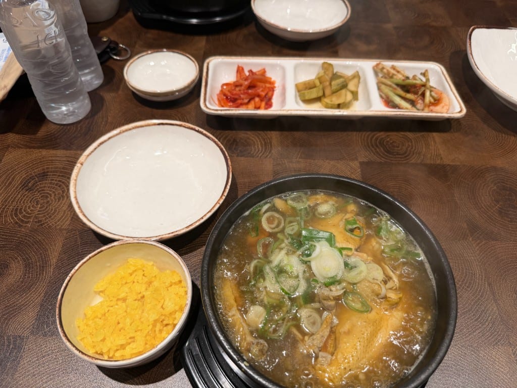 Taebaek samgyetang with banchan — yellow rice, golden bowl, pickles