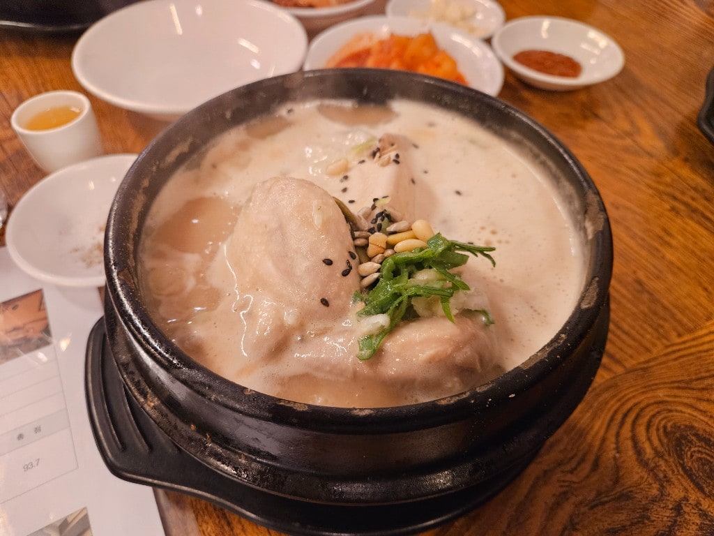 Creamy Tosokchon samgyetang in a black pot with side dishes